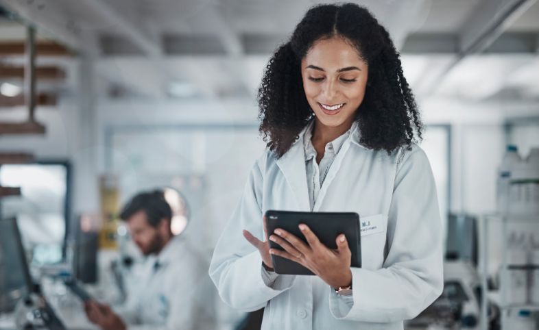 Lady in white lab coat holds iPad in her hands