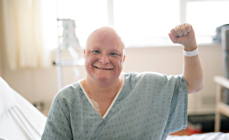 Cancer patient in hospital wearing a hospital gown with arm up in the air